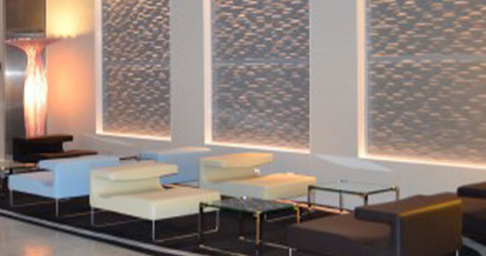 Bild der Lobby des Hilton Hotels in Frankfurt. Die Lobby ist Bestuhlt und mit gedimmten Licht ausgestattet, das in Wandpaneelen integriert ist.
